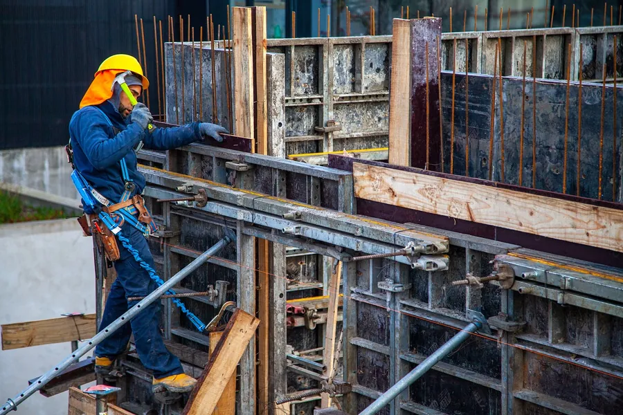 Worker setting steel formwork for a poured concrete wall, Bartlesville
